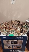 Overview of approximately fifty small porcelain Wade figurines displayed on a cracked mirror surface.