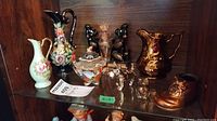 Shelf display of Wade pitcher, small decorative shoe, black bear figurine bookends, two clear glass sugar bowls, and floral/white pitchers and porcelain dish.