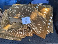 Folded brown African mud cloth with white traditional geometric patterns and frayed edges on a black metal surface.