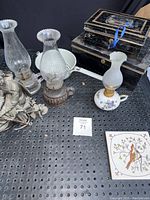 Overview of two oil lamps, decorative small oil lamp, two lock boxes, ceramic bowl and trivet
