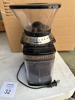 Front angle view of the Cuisinart DBM-8 coffee grinder on white surface with packaging behind.