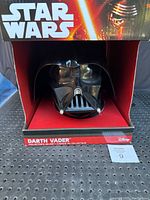 Front view of the Darth Vader collector's helmet inside the display box showing the full face and packaging.