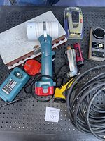 Overview of assorted tools and electronics including the Makita converted travel light-fan, charger, handheld staple gun, flashlight, coiled cable, and white styrofoam holder