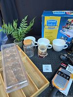 Overall lot showing expandable shelf box, assorted mugs, bamboo utensil tray, clear plastic egg holder, and OXO grater.