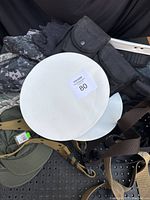 Close-up view of two white sailor hats on top of camouflage clothing, with belts and pouches around.