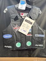 Front view of black leather Tipperary Pro Max rodeo vest size medium showing multiple sponsor stickers and chest padding.
