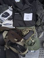 Photo shows multiple military clothing items including a black uniform shirt with 'ADAMS' patch, camouflage clothing, tactical belts in various colors, and gloves in packaging.