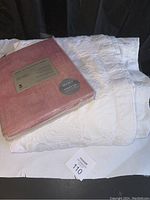 White king sized bedspread with rose pattern laid out with unopened West Elm curtain panels package on top.