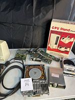 Overview shot displaying all items in the lot including CPU stand box, circuit boards, hard drives, speaker and cables arranged on black cloth background.