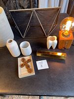 Group photo of industrial light, metal shelf, three ceramic vases, gold pencil holder, box with wooden tokens on black surface