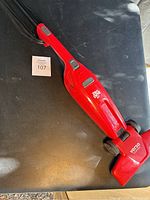 Red Dirt Devil Versa Clean vacuum cleaner laying on a black surface showing the front and top view with visible brand and model markings.