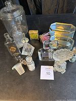 Group photo showing all glass containers and perfume bottles on display, including large jar, various bottles, stoppers, and decorative items.