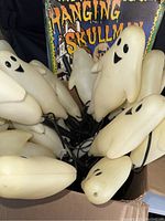 Box with multiple cream colored ghost shaped string lights with black facial features and wiring visible, showing vintage style design
