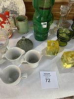 Wide view of arranged vintage household items including Selb Bavaria creamers, Kahlua bottle, Japanese teapot, glass candle holders, and ceramic pieces