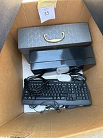 Photo showing Logitech wired keyboard, two wired computer mouses, and two decorative filing bins inside cardboard box.