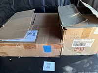 Two cardboard boxes, one with shipping labels and another partially opened labeled 'sil corner', containing lightbulbs.