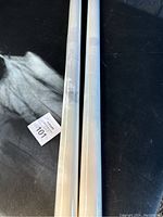 Two rolls of white privacy window film placed side by side on a black surface, wrapped in clear plastic.