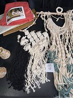 Photo showing salmon and beige colored UASHMAMA recycled paper bags, macrame wall hangings in various colors, partially coiled wood pole, and visible tassels