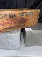 Photo displaying the wooden Encyclopedia Americana crate with printed labeling and two metal milk crates underneath.