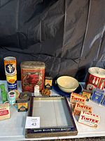 Full lot showing variety of vintage tins, Sunshine Biscuits box topper, enamel bowl, and fabric dye boxes arranged on surface with black backdrop.