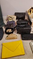 Overall view of the lot with various handbags and clutches arranged on floor showing different styles and textures.