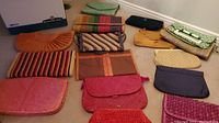 View of entire collection of woven bags and clutches arranged on floor showing variety of colors and styles