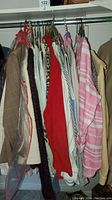 Multiple women's blouses and jackets hanging on rack showing various colors and styles including red, striped pink and white, animal print, tan jacket, and dark knit item