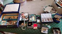 Wide shot showing assortment of costume jewelry including necklaces, earrings, bracelets and an antique jewelry box, all arranged on a table.