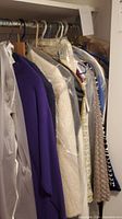 Photo showing garments hanging on rack, including purple and cream jackets, some dry-clean protected.