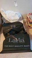 Three original dust bags in black and white fabric with brand logos LaVia and Sandra Angelozzi.