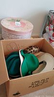 Box with several hats including green, beige, leopard print, and white beret-style hat.