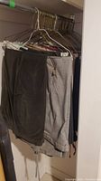 Photo showing multiple pairs of skirts and pants hanging on hangers in a closet