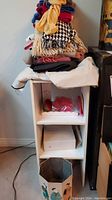 Stack of scarves on top of a small white wooden shelf with two visible compartments and items inside.