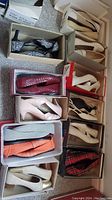 Overview photo of eleven pairs of lady's shoes in boxes, including flats and low heels of various colors and patterns.