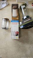Three small kitchen appliances: Braun coffee grinder in box, Eurotech Maxi food chopper with box, and Waring blender with glass pitcher.