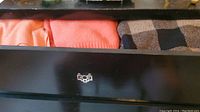 First drawer with coral, peach, and black checkered sweaters visible.