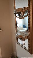Side-angle view showing the mirror and one of the two decorative gold shelves.