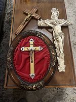 Three crucifixes on a wooden surface showing size and detail