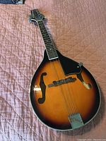 Full view of Harmony mandolin with sunburst finish on quilted fabric surface.