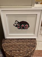Framed Inuit Native American stone block print by Angela Herve depicting a stylized snoozing bear in black, red, and white.