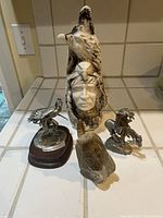 Four Native American themed statues arranged on a tiled surface showing scale and relative size.