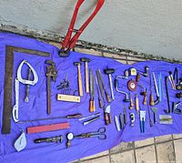 All tools laid out on blue tarp. Visual overview of the entire collection shows variety of vintage hand tools in used condition.
