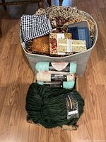 Two baskets filled with fabric pieces, yarn balls, ribbon rolls, and trims displayed on a hardwood floor.