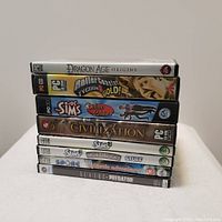 Stack of eight assorted PC game boxes and cases showing spine titles