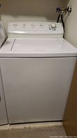 White Frigidaire top-loading washing machine showing front and top lid closed; positioned between washer hookups.