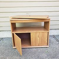 Wooden console with open door showing interior storage space and detached top panel