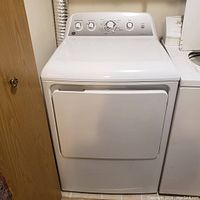 Full front view of white GE Sensor Dry Dryer showing door closed and location against cabinetry and washer.