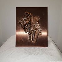 Front of the brushed copper plaque showing raised saxophone, sheet music, and chrysanthemum design