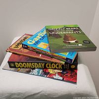 Stack of comic books and graphic novels showing titles and covers clearly in a pile