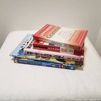 Stack of six Japan-themed books including grammar, phrase, dictionary, and comic books.